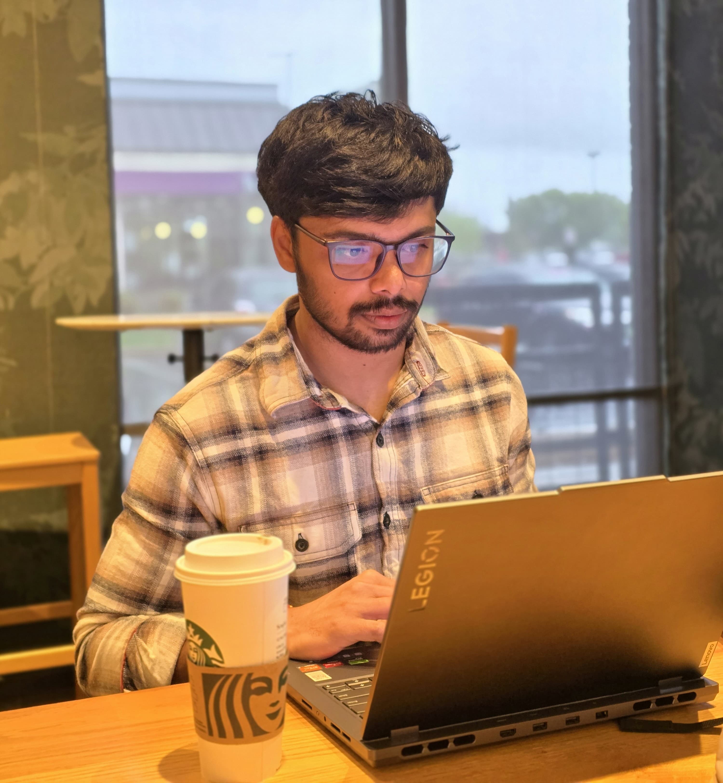 Srujan Chidarla working on his laptop at a café